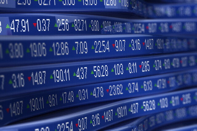 Electronic stock market display board showing various stock prices with some figures in green indicating gains and some in red indicating losses.