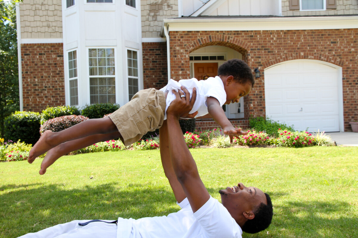 African American father and his son playing outside in their yard