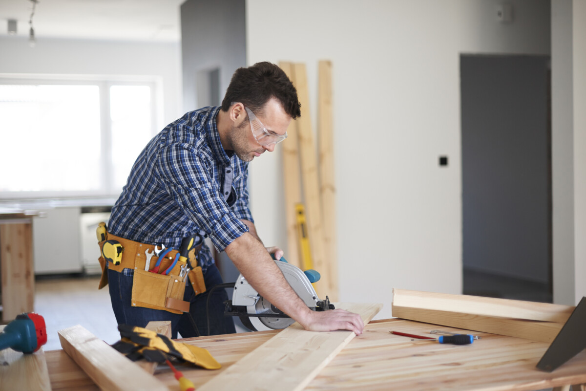 Craftsman precision: a focused carpenter measuring wood before cutting in a well-organized workshop.