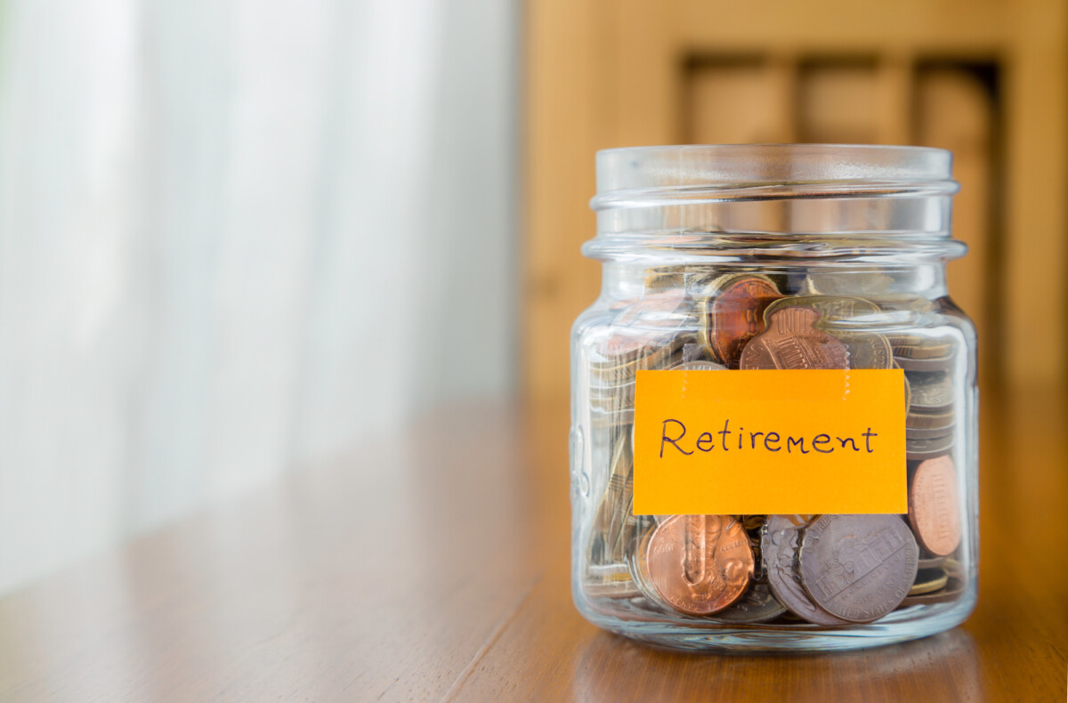 A glass jar filled with coins and labeled 'retirement', symbolizing the concept of saving money for the future.