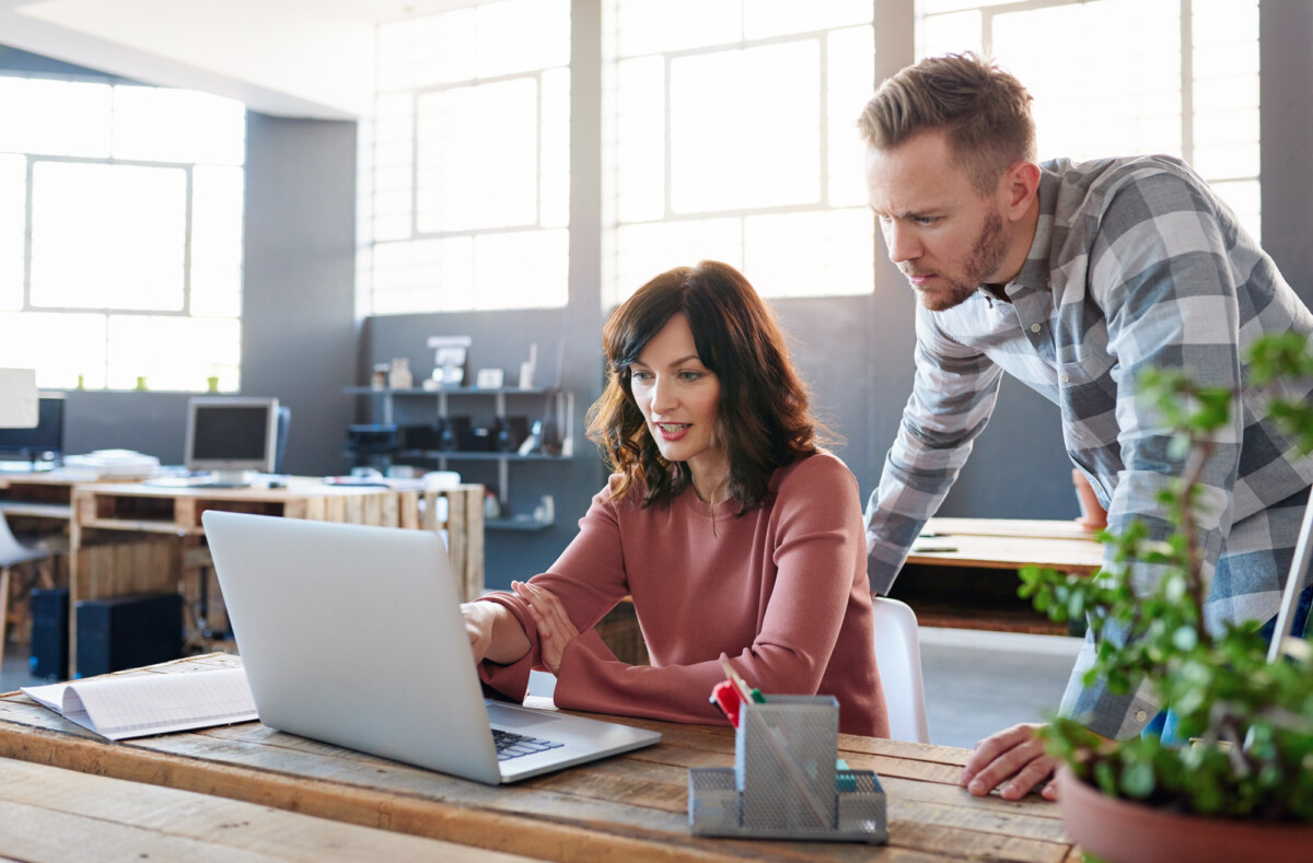 Two professionals collaborating at a laptop in a modern office space.