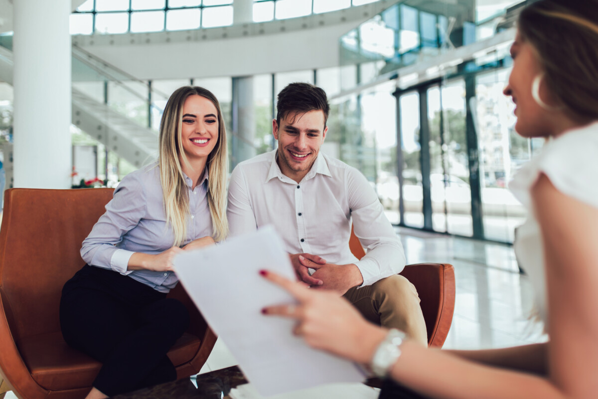 Two professionals smiling during a pleasant meeting with a colleague in a modern office setting.