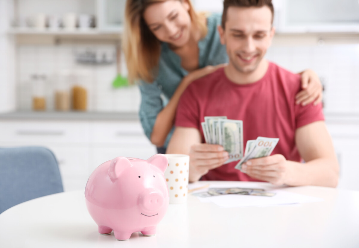 A happy couple managing their finances together with a piggy bank in the foreground, symbolizing savings and financial planning.