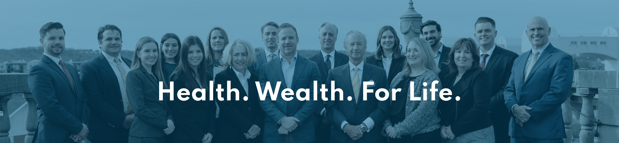 A group of professionally dressed people stand together outdoors, smiling at the camera, with the text 