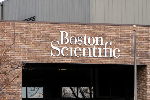 The exterior of a brick building with large white letters spelling "Boston Scientific" mounted on the wall.